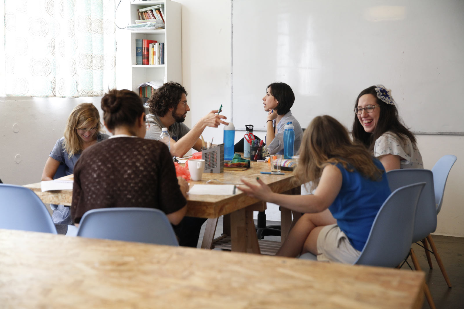 People talking and laughing around a classroom table at Ulpan Bayit.